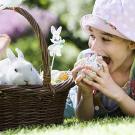 Niña comiendo un huevo de pascua. Tarjeta virtual para los niños