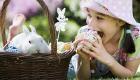 Niña comiendo un huevo de pascua. Tarjeta virtual para los niños