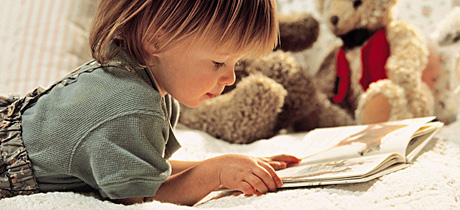 Niña lee libro en la cama